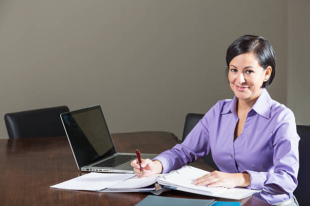 istock Hispanic office worker writing in binder, sitting in office 186664482