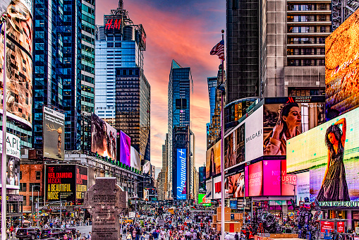 New York, USA; May 31, 2023: The famous Times Square, which is the most famous place in the Big Apple, located in the heart and lung of Manhattan, under a reddish-orange sky at sunset.