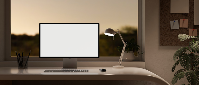 Modern home office in the evening with a white-screen computer, a table lamp, and a pencil stand on a desk near by the window. front view. 3d render, 3d illustration
