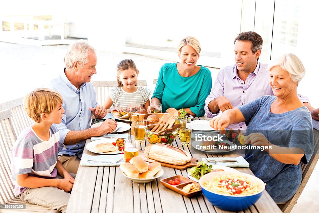 Tres generaciones de la familia de disfrutar de un almuerzo Al aire libre - Foto de stock de Mesa de comedor libre de derechos