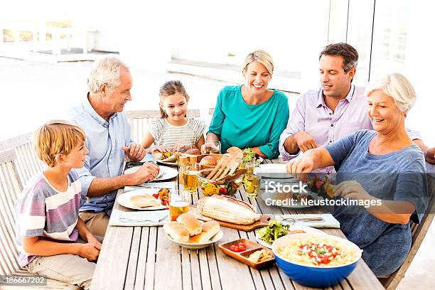 Tres Generaciones De La Familia De Disfrutar De Un Almuerzo Al Aire Libre Foto de stock y más banco de imágenes de Mesa de comedor