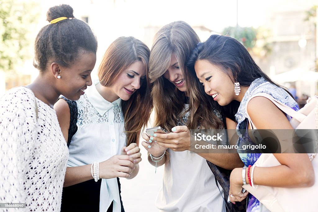 Четыре молодые женщины использование смартфона - Стоковые фото 18-19 лет роялти-фри