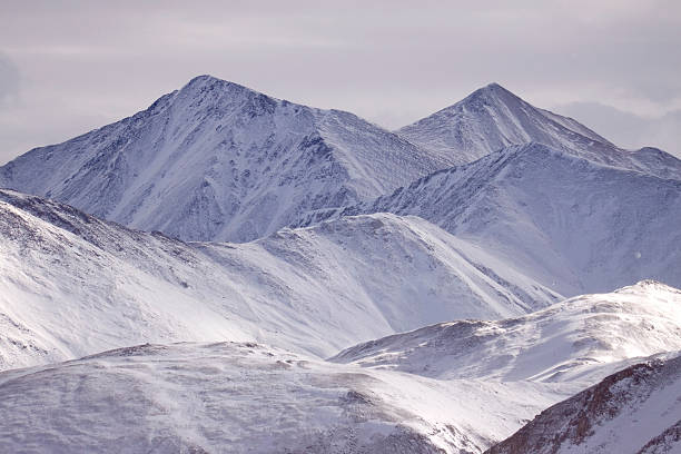 As snow falls looking from the continental divide, snow covered Grays (on right - 14,270 ft) and Torreys Peak (14,267 ft) are two sister peaks separated by about 1/2 mile saddle. They are two of 54 fourteeners in Colorado and are mountains in the Front Range region of the Rocky Mountains in Colorado.