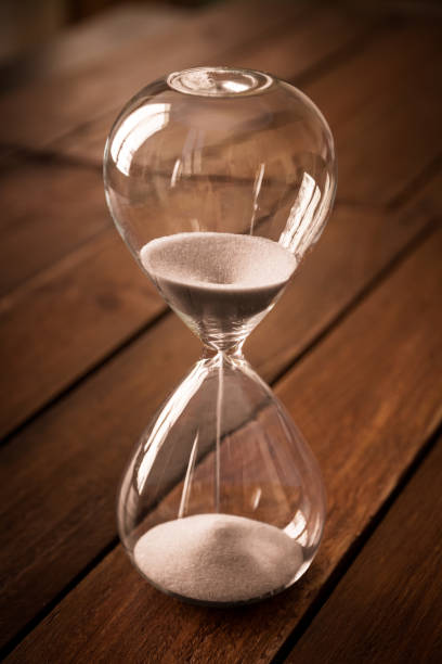 istock Hourglass containing white sand on a rustic wooden board 1866685553