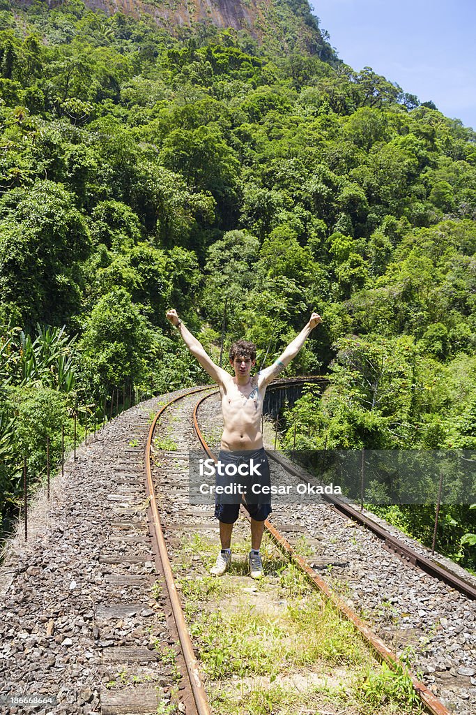 Rail adventure Young man cheering on railroad bridge. Achievement Stock Photo