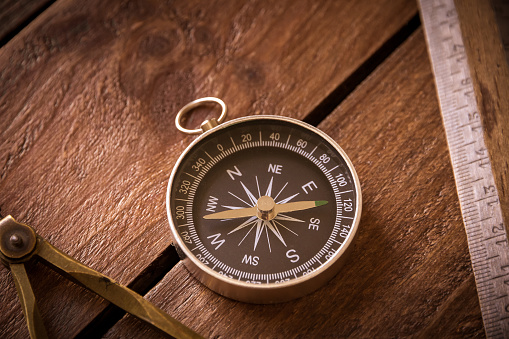 Vintage ruler, drawing and navigational Compass on a rustic wooden board