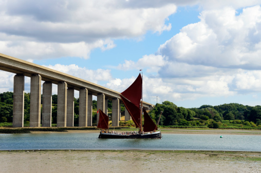 A traditional wherry carrying tourists on the River Orwell at Wherstead, near Ipswich in Suffolk, England, at low tide.