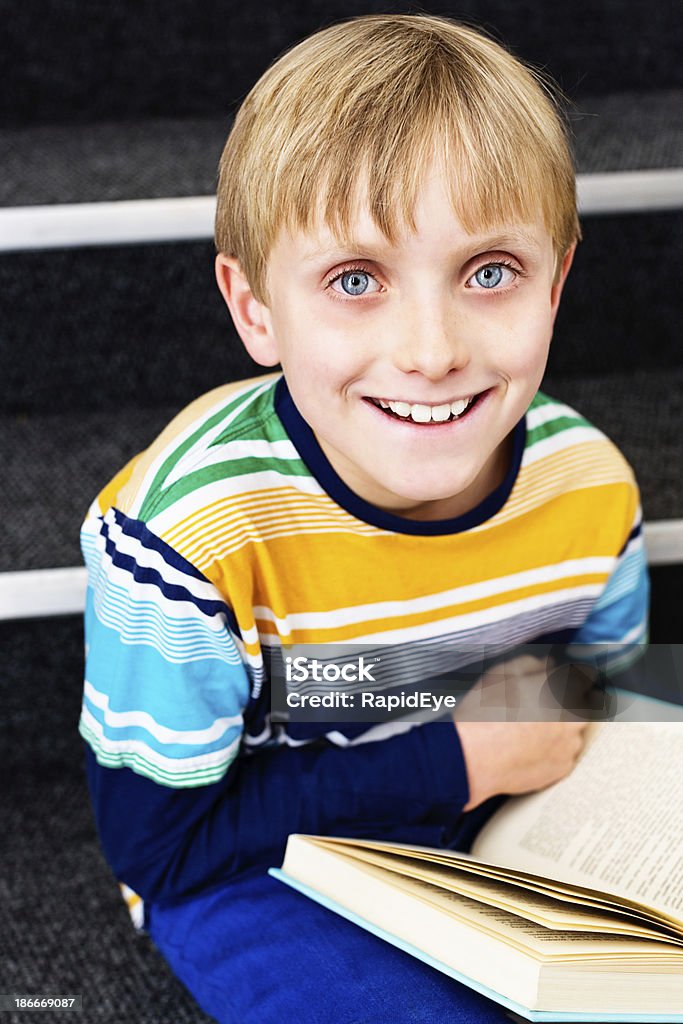 Reading? I love it! Happy blond schoolboy in library This happy blond elementary school boy sits, smiling, on the library steps with his book. Learning can be fun! 10-11 Years Stock Photo