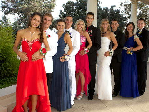 A large group of happy teenagers at the prom posing outdoors.