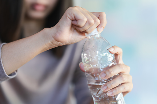 Women holding drinking bottle and opening the cap of a water bottle to drink water.