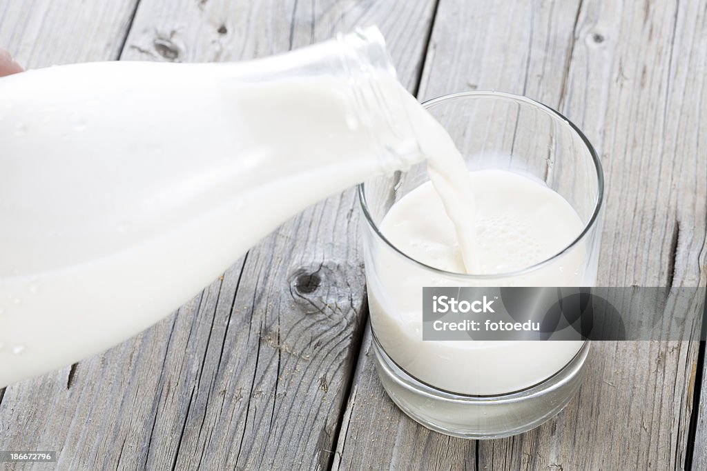 Bottle and glass of milk Serving fresh milk in a glass vase on a wooden table Milk Stock Photo