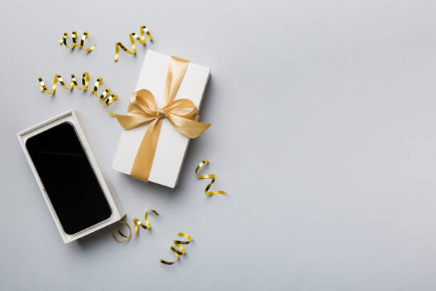 istock Opened gift box with gold ribbon and smartphone on color background, top view. Blank open box packaging mockup , Template for your design - branding mockup 1866732910