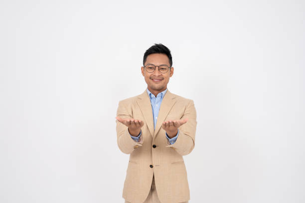 istock A handsome businessman is opening his palms at the camera while standing on an isolated background. 1866732922