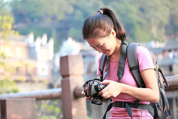 young asian woman tourist taking photo at fenghuang anceint city,hunan province,china