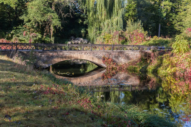 istock Decorative arched stone footbridge with railing in autumn park 1866740429