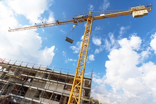 Cranes and construction site work in progress against a blue sky with white clouds.