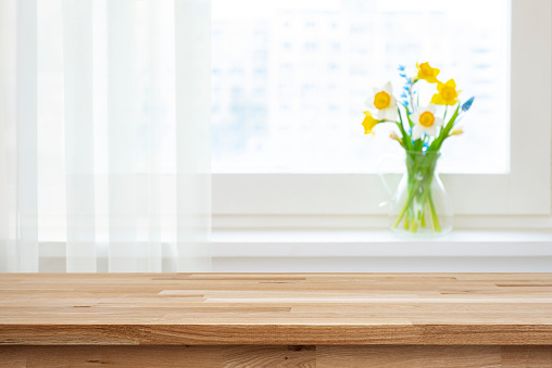 Empty wooden table top for product montage and blur window sill with beautiful flowers