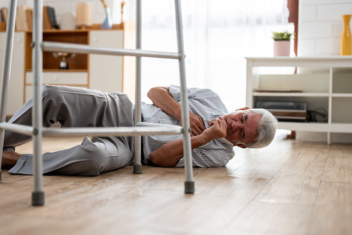 Asian senior elderly male fall on the ground while walk alone in house. Mature older grandfather having an accident and fainting while doing physical therapy after retirement in living room at home.