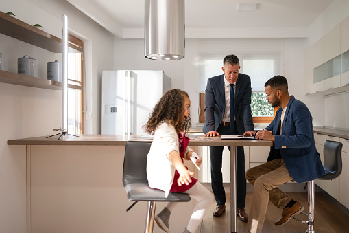 Mid adult man talking  with insurance agent while sitting in luxury Kitchen.