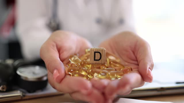 Vitamin D3 capsules in the hands of a doctor, closeup