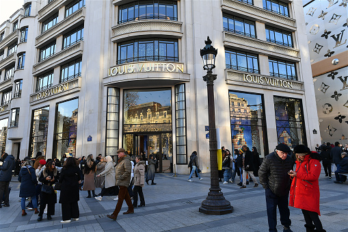 Paris, France-12 16 2023: Group of people passing in front of the Louis Vuitton flagship store located on the avenue of the Champs-Elysées in Paris, France.