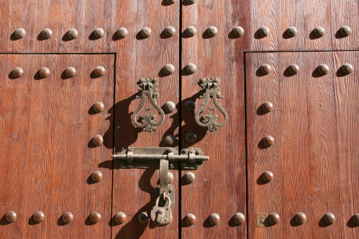 Wooden door of a church in Almeria, Spain. Old architecture - knocker, bolt, padlock.