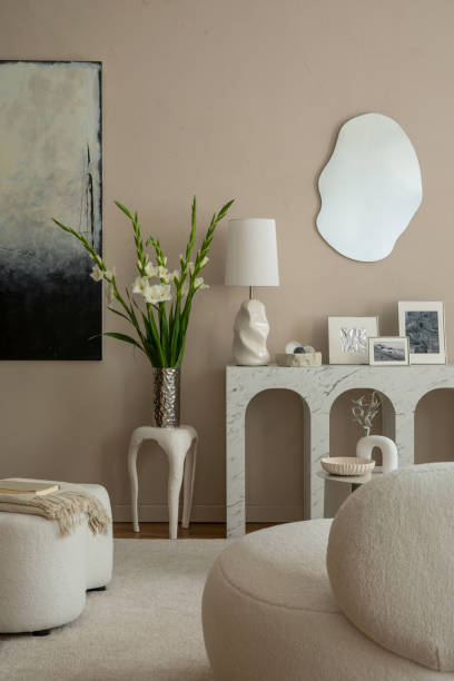 istock Creative composition of elegant living room interior with mock up poster frame, marble arch console, vase with flowers, boucle pouf, beige plaid, lamp and personal accessories. Home decor. Template. 1866771070