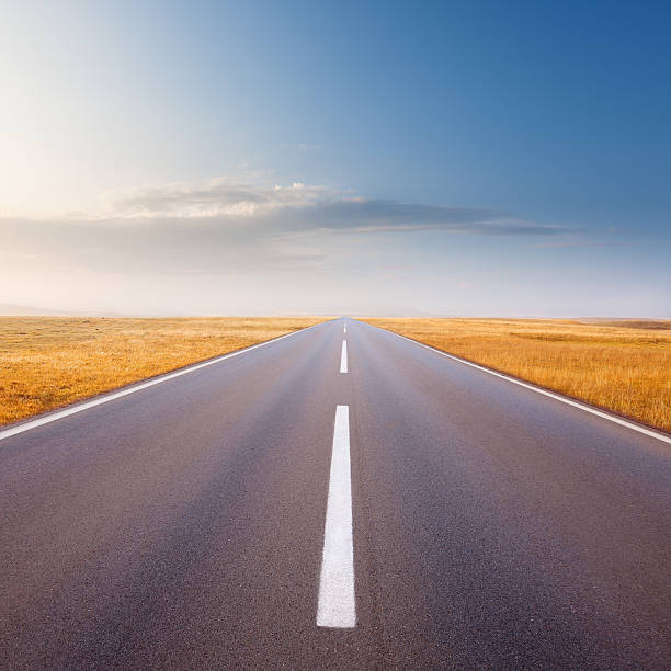 istock Driving on an empty road at bright sunny day 186677257