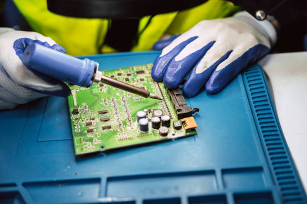 istock Electrician technician using hot soldering iron to fix repair small electrical digital computer circuit board fix repair with solder tin and lead 1866780991