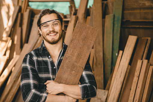 Portrait young carpenter artisan hand wood crafting man with wooden panel happy smiling
