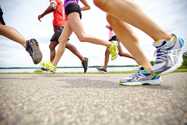 Low side view of athletes running on a track Low angle side view of athletes running on an outdoor track running jogging men human leg stock pictures, royalty-free photos & images