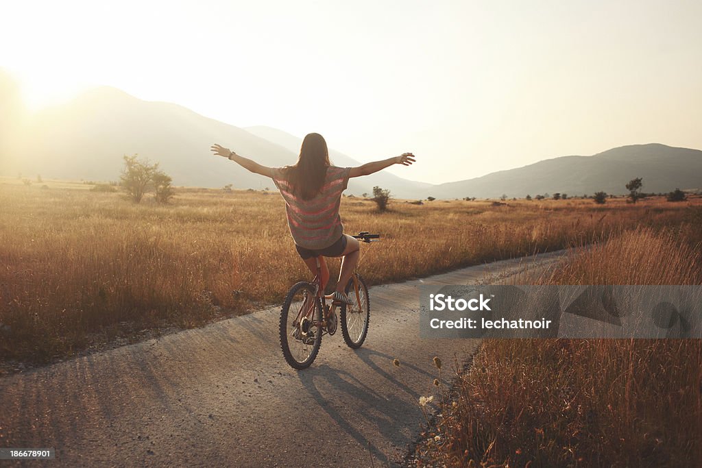 summer joyride vintage toned young brunette on a bicycle, lit by the Autumn sunset. Cycling Stock Photo