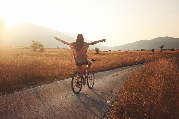 summer joyride vintage toned young brunette on a bicycle, lit by the Autumn sunset. freedom stock pictures, royalty-free photos & images