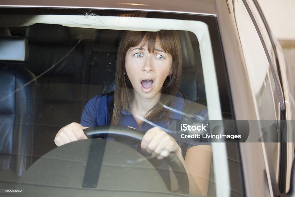 Cracked Windshield Driver shocked by huge rock chip in windshield. Focus is on the woman. Windshield Stock Photo