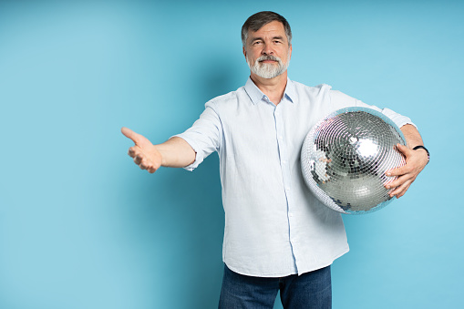 Photo of positive old man hold disco ball isolated on blue background