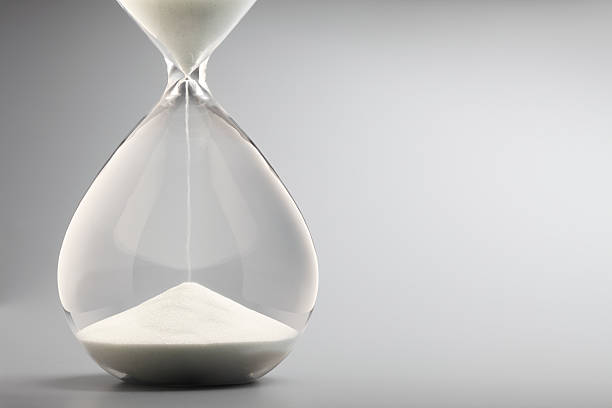 Sand Pouring Into Bottom Of Hourglass On Gray Background An hourglass. hourglass photos stock pictures, royalty-free photos & images