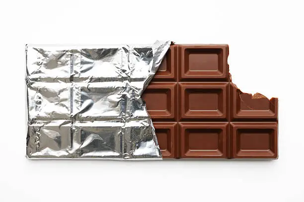 Close-up shot of chocolate bar with a missing bite in silver foil isolated on white background with clipping path.