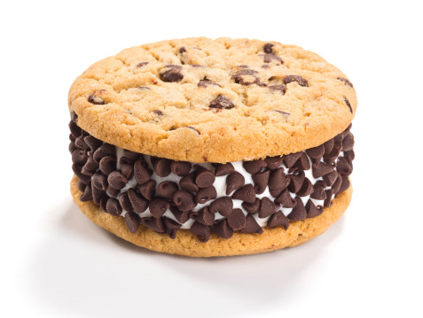 An ice cream sandwich made from vanilla ice cream squeezed in between two chocolate chip cookies and covered in chocolate chips.