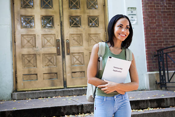 Applying for scholarship A Hispanic student walking out of school with Scholarship application papers. puerto rican ethnicity stock pictures, royalty-free photos & images