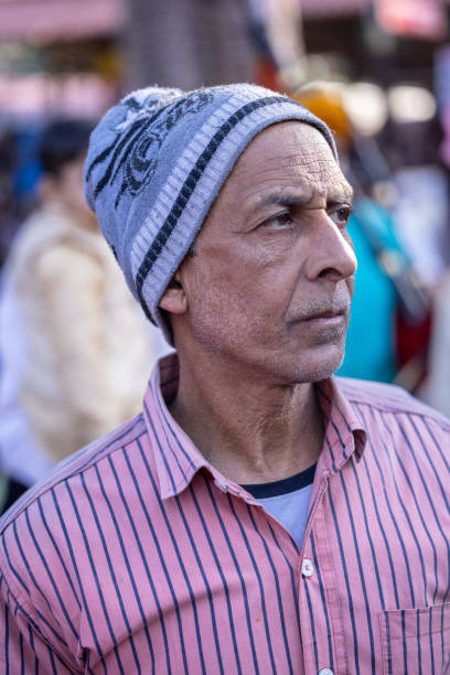 Faridabad, Haryana, India - 4 February 2023: Portrait of an old male with winter hat on his looking for some activities at surajkund craft fair.