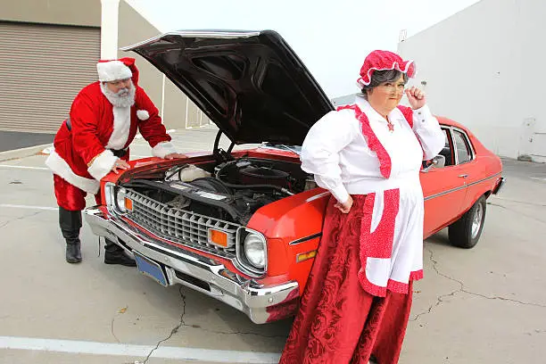 Mrs. Claus is annoyed that Santa's vintage car is broken down in an industrial area.