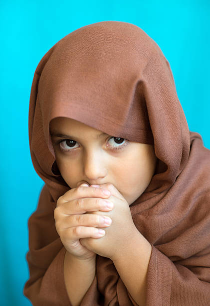 Muslim Turkish girl looking at camera, hand clasped.