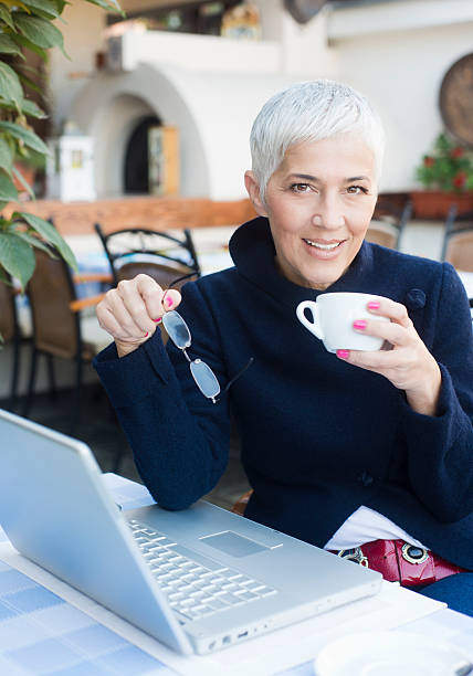 istock Mature woman with glasses using laptop at a cafe 186683977