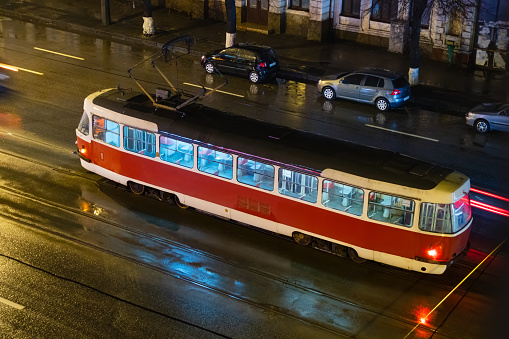 An old tram on a city street on a rainy evening, view from above. Wide multi-lane asphalt road