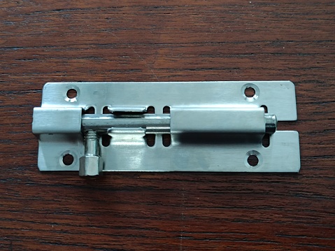 Stainless door latch with dark brown wood background