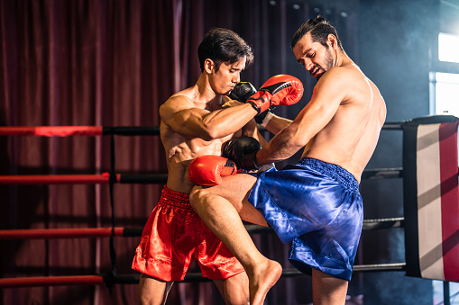 Two young professional boxer having a competition tournament on stage. Attractive male athlete fighters muscular shirtless punches and hitting competitor enjoy boxing exercise in the ring at stadium.
