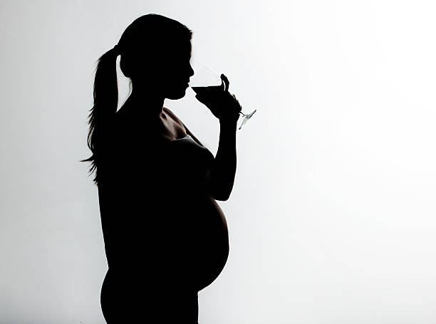 donna incinta tenendo un bicchiere di alcol - abdomen addiction adult alcohol foto e immagini stock