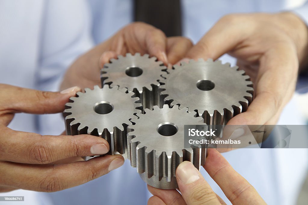 Business People With Gears Close up of business people hands with cogs. Adult Stock Photo