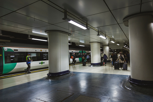 London, England - May 01, 2023: Underground tube metro with motion moving red subway train in Victoria sign nobody on platform station