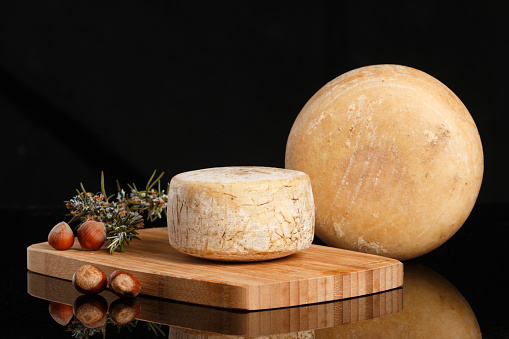 Artisanal and natural whole cheese, placed on a wooden board and without labels. Advertisement space for text.
